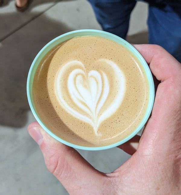 I am holding a coffee mug in front of me with a classic heart in latte art style