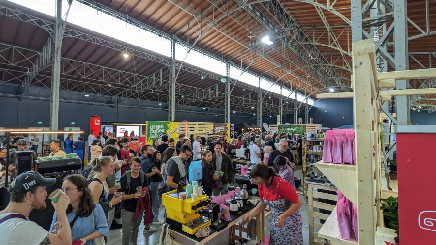 A large hall serves a venue of the festival with many people standing at booths